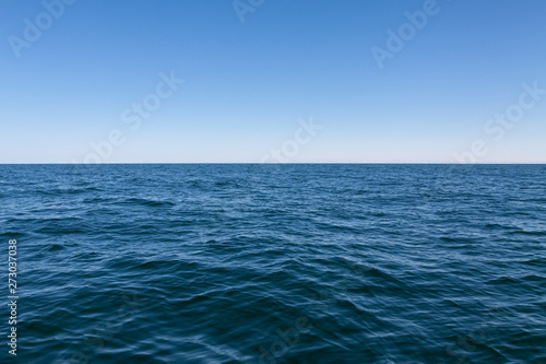 Background, small waves of the sea, and above them the blue sky.
