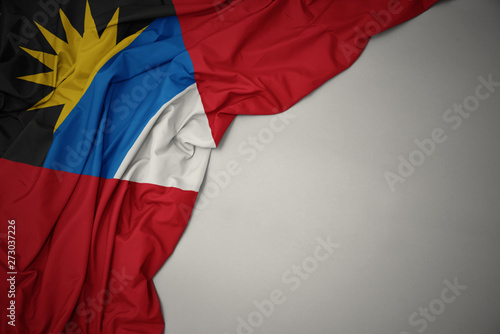 waving national flag of antigua and barbuda on a gray background.
