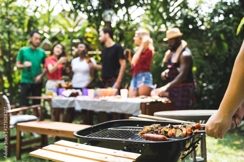 Young boy cooking meat on barbecue grill for Group of friends at summer outdoor party and holidays concept..