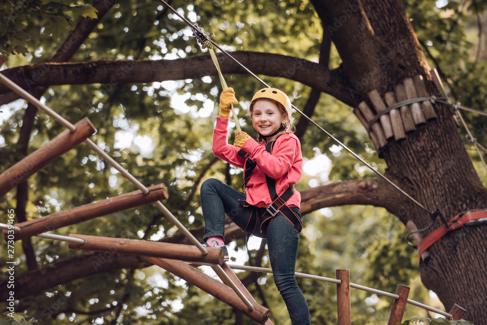 Hike and kids concept. Toddler kindergarten. Eco Resort Activities. Happy child boy calling while climbing high tree and ropes. Children summer activities.