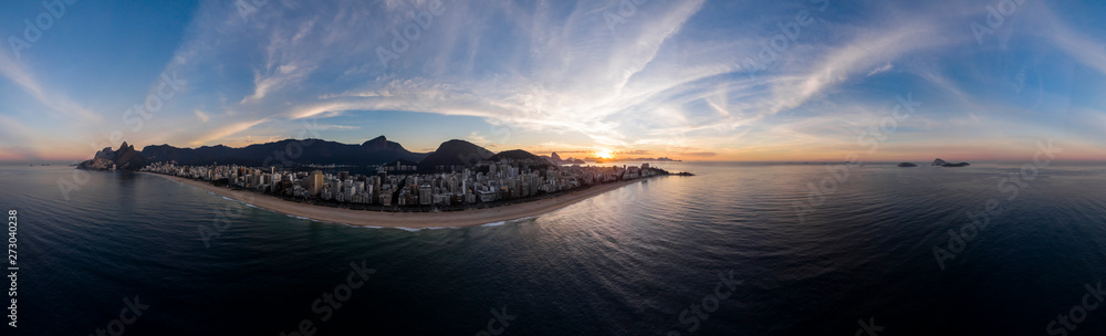 Sunrise 360 degree full panoramic aerial view of Rio de Janeiro with Ipanema and Leblon beach in the foreground and the wider cityscape in the background against a colourful blue sky