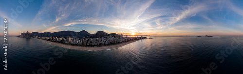 Sunrise 360 degree full panoramic aerial view of Rio de Janeiro with Ipanema and Leblon beach in the foreground and the wider cityscape in the background against a colourful blue sky