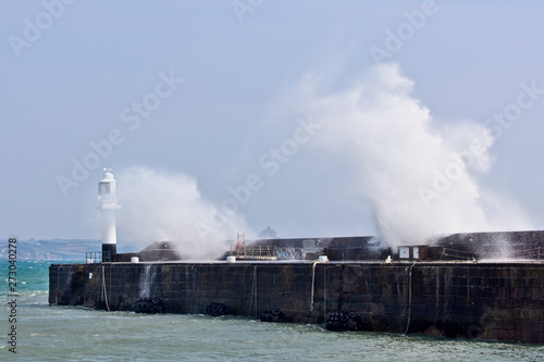 Waves breaking over Penzance's harbour wall and lighthouse, Cornwall, England, UK. © tonymills