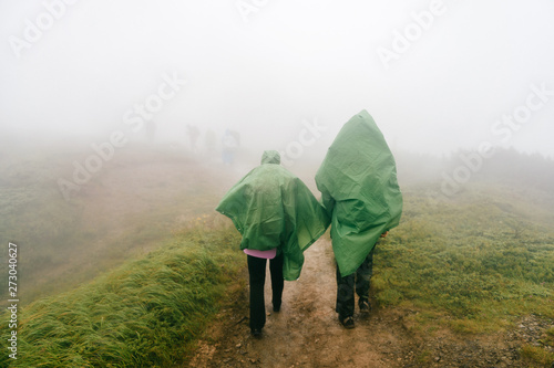 Hiking. Backpackers hiking up the foggy mountains. Mountain trekking. Men with backpacks on trek.