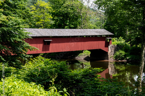 A red historic covered bridge surrounded by trees