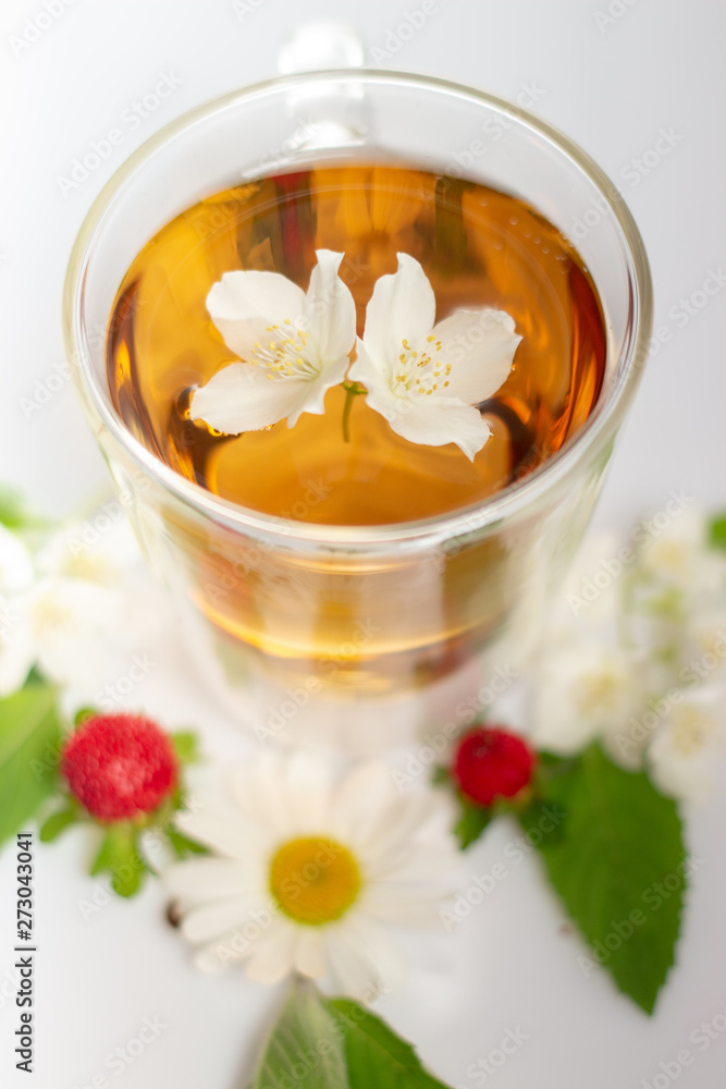 green tea with jasmine in a transparent glass thermomug on a white background green tea with jasmine in a transparent glass thermomug on a white background