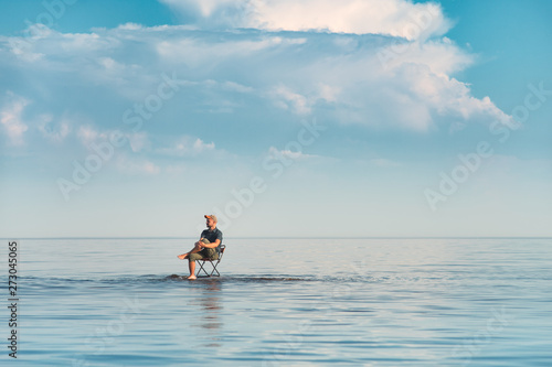 A man sits on a chair in the water