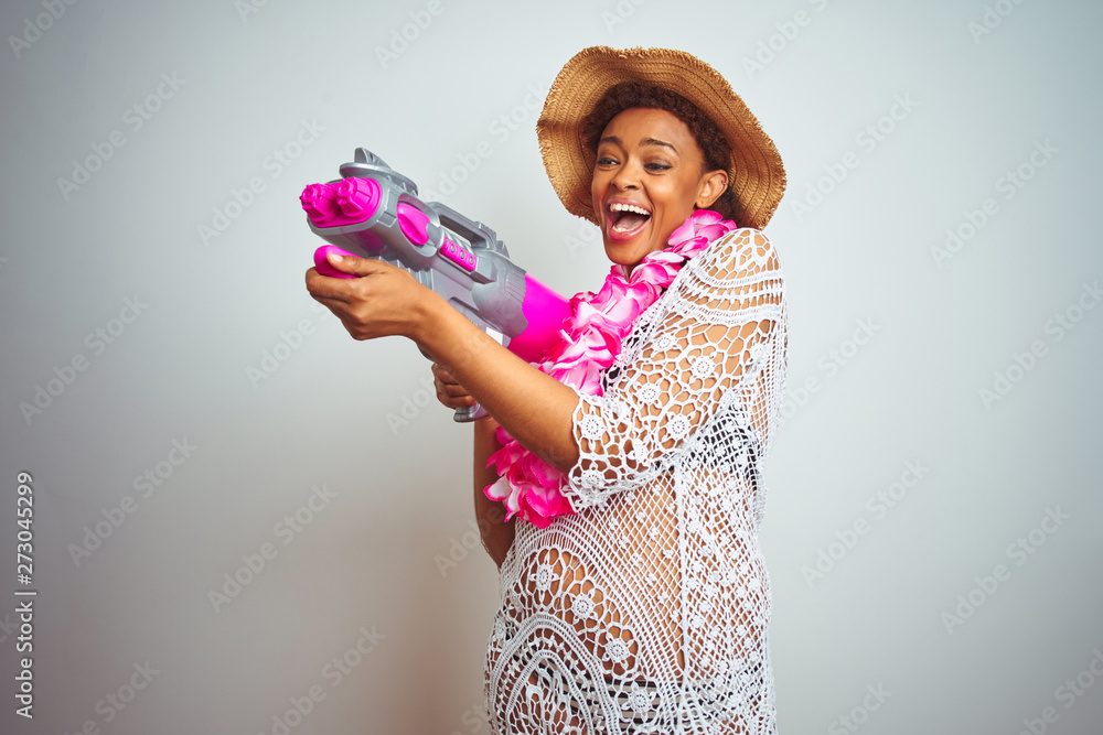 Young african american woman with afro hair wearing flower hawaiian lei and water gun with a happy face standing and smiling with a confident smile showing teeth Young african american woman with afro hair wearing flower hawaiian lei and water gun with a happy face standing and smiling with a confident smile showing teeth