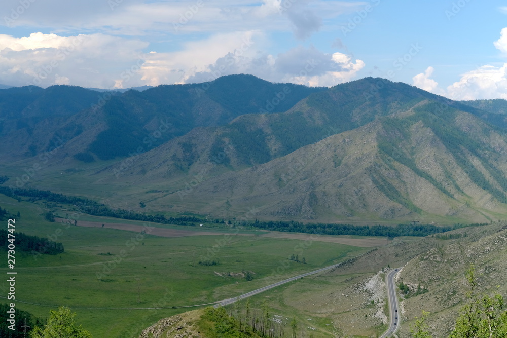 Mountain landscape. At the foot of the mountains, plain and the road with cars