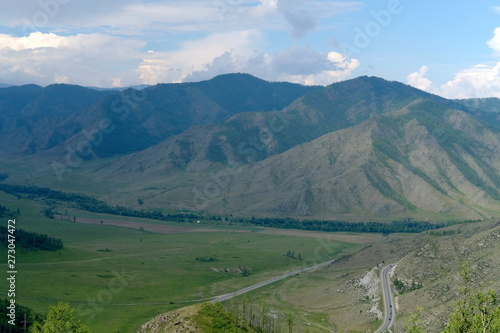 Mountain landscape. At the foot of the mountains, plain and the road with cars