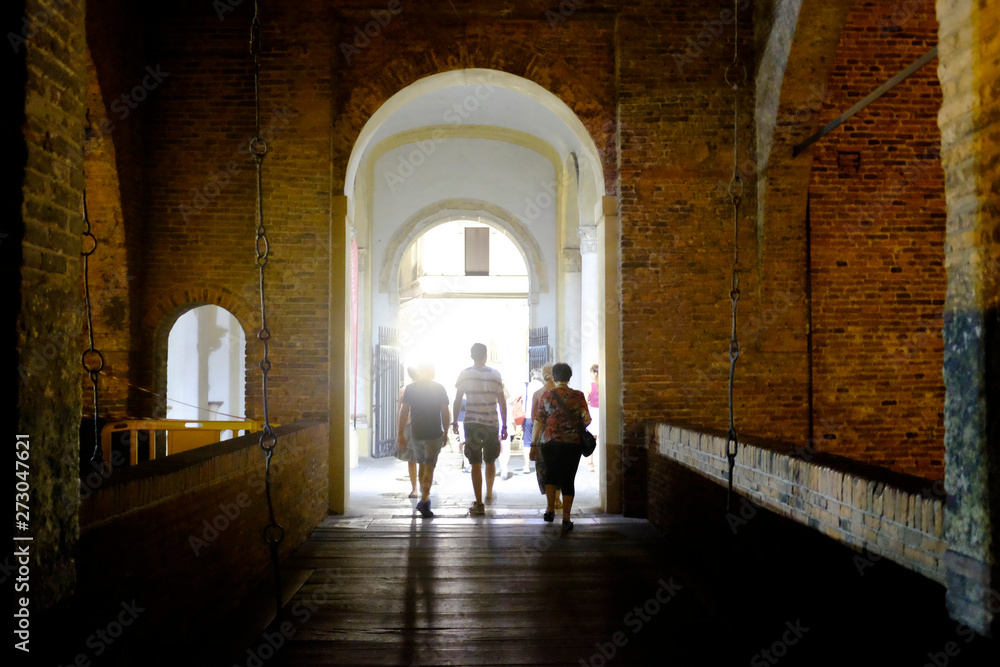 Some people walk on the drawbridge of the castle of Ferrara in the night. Ferrara, Italy