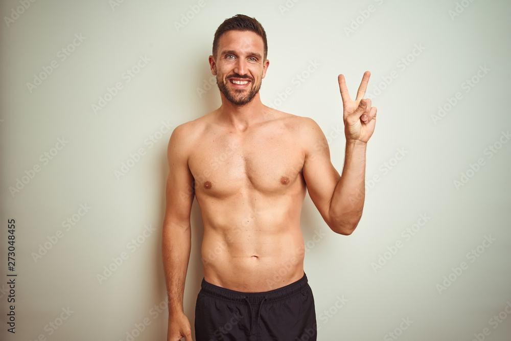 Young handsome shirtless man over isolated background smiling with happy face winking at the camera doing victory sign. Number two.