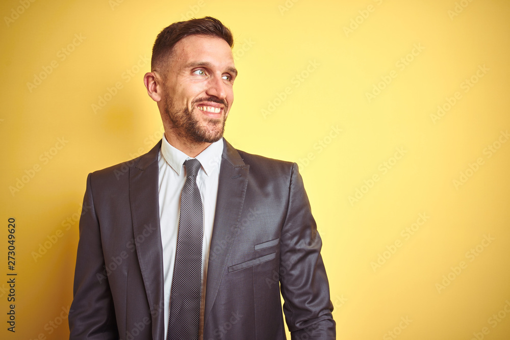 Young handsome business man over yellow isolated background looking away to side with smile on face, natural expression. Laughing confident. Young handsome business man over yellow isolated background looking away to side with smile on face, natural expression. Laughing confident.