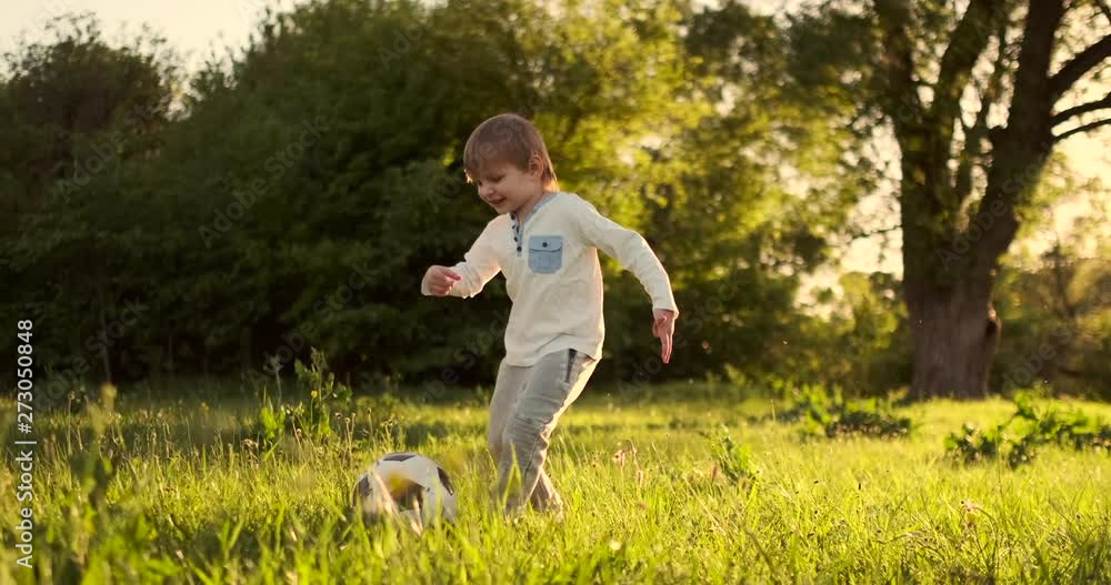 Happy boy running with soccer ball running at sunset in summer field Happy boy running with soccer ball running at sunset in summer field