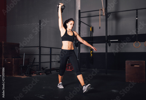 Young woman realizing indoor exercises with kettlebell