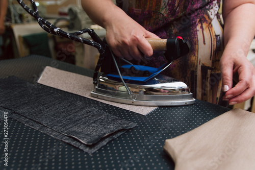 A woman strokes the fabric for further sewing. Tailor ironing clothes