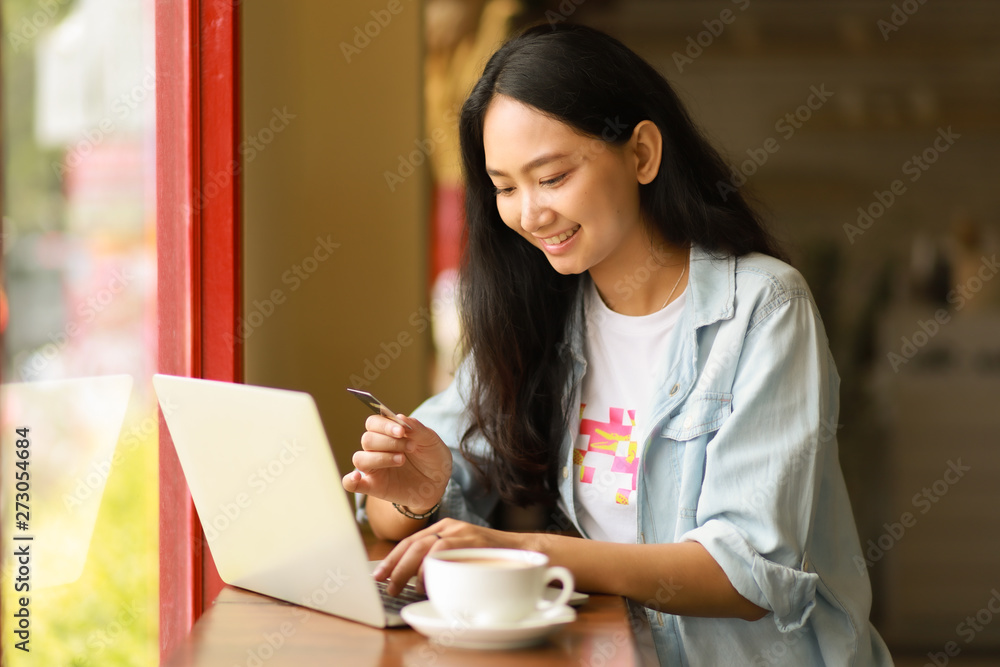 Asian woman using laptop working and drink coffee in cafe Asian woman using laptop working and drink coffee in cafe