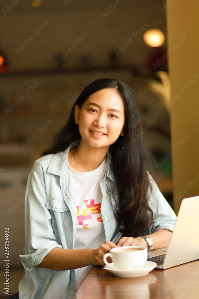 Asian woman using laptop working and drink coffee in cafe Asian woman using laptop working and drink coffee in cafe