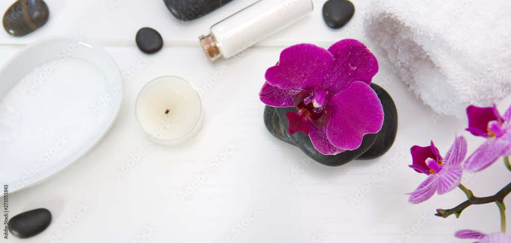 Spa setting with pink orchids, black stones and bath salts on white wood . Spa setting with pink orchids, black stones and bath salts on white wood .