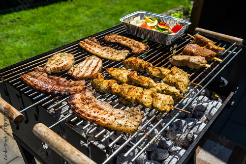 Different types of meat fried on the home grill, standing on a home garden on the paving stone.