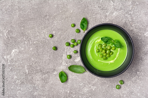 Soup of young green peas with basil leaves on gray