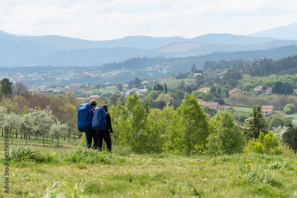 A couple is traveling with backpacks across the field A couple is traveling with backpacks across the field