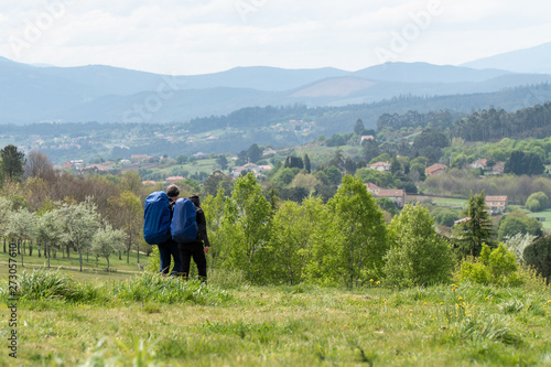 A couple is traveling with backpacks across the field