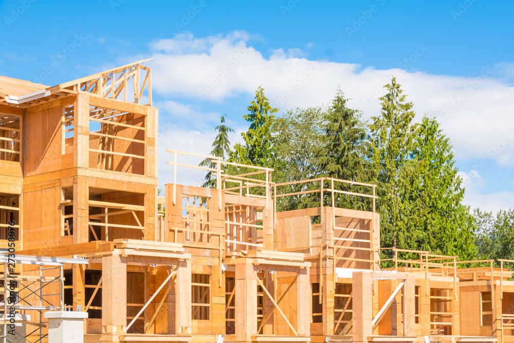 New condo building under construction on sunny day on blue sky and trees background New condo building under construction on sunny day on blue sky and trees background