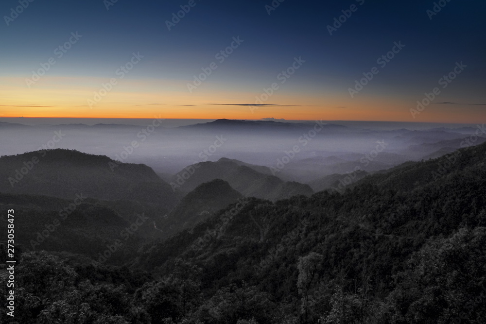 Obraz premium Mountain view misty morning of top hills around with sea of fog with red and yellow sun light in the sky background, sunrise at Doi Ang Khang, Monzone view point, Chiang Mai, Thailand.