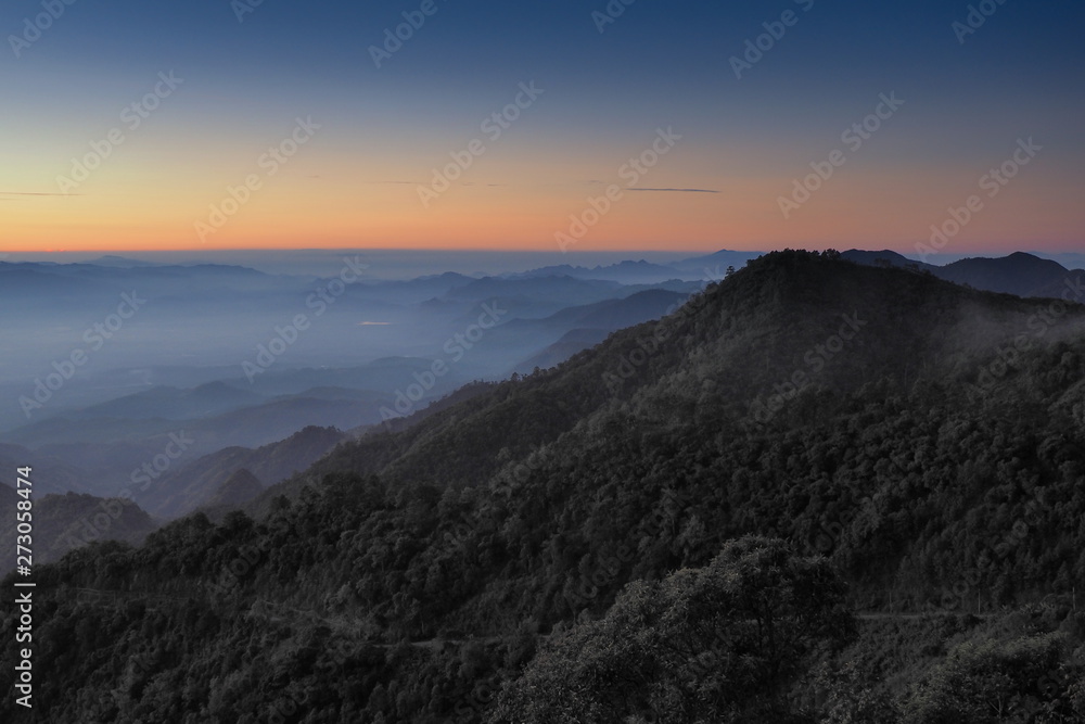 Mountain view misty morning of top hills around with sea of fog with red and yellow sun light in the sky background, sunrise at Doi Ang Khang, Monzone view point, Chiang Mai, Thailand.