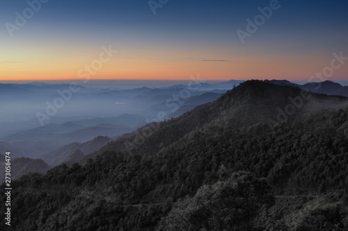 Mountain view misty morning of top hills around with sea of fog with red and yellow sun light in the sky background, sunrise at Doi Ang Khang, Monzone view point, Chiang Mai, Thailand. © Yuttana Joe