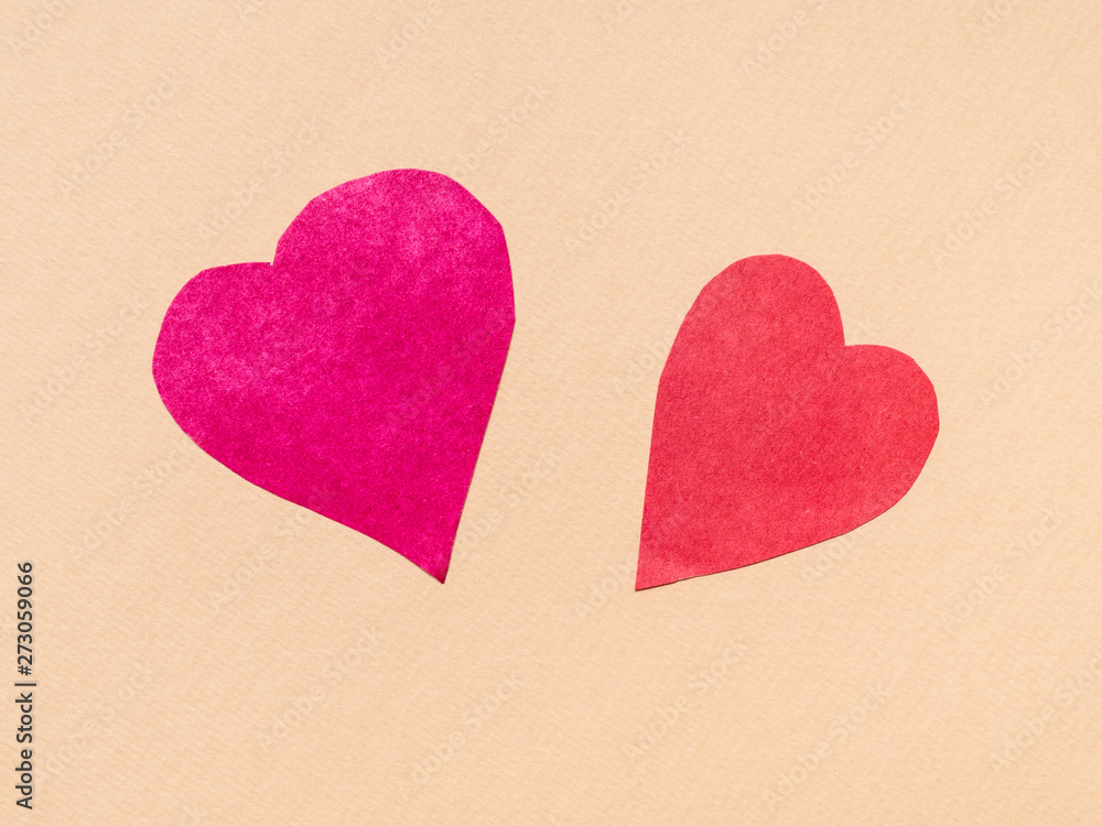 two hearts cut from red papers on beige paper two hearts cut from red papers on beige paper