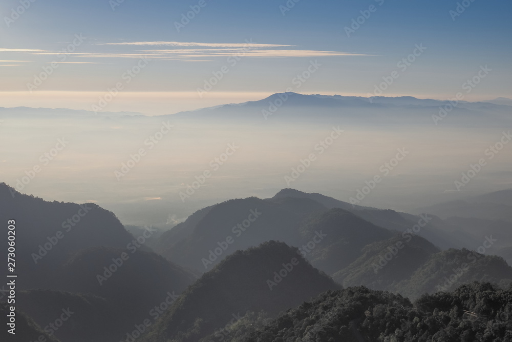Mountain view misty morning of top hill around with sea of mist and blue sky background, sunrise at Doi Ang Khang, Monzone view point, Chiang Mai, Thailand.