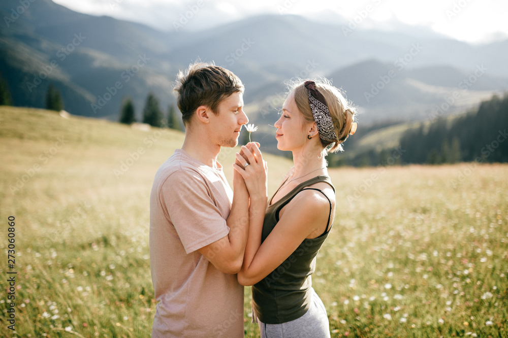 Lifestyle loving couple hugging at nature among mountains in summer.
