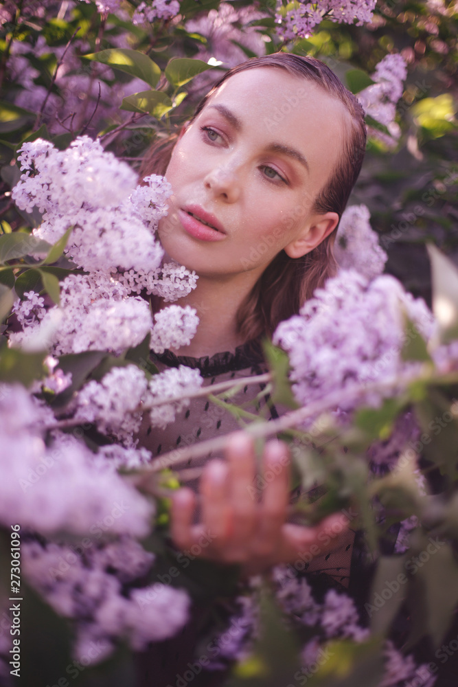 Young beautiful woman with fantasy make up posing with lilac flowers