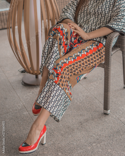 Beautiful girl model posing on the balcony in bright clothes.