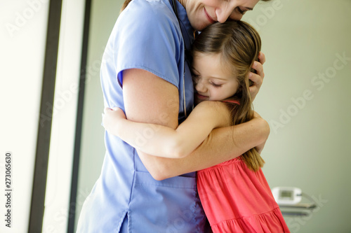 Young girl hugs woman doctor