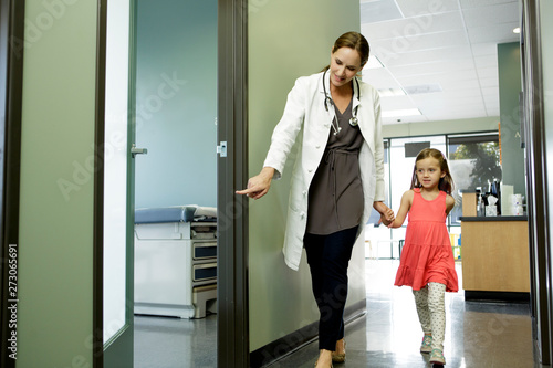 Woman doctor walks young patient to examination room