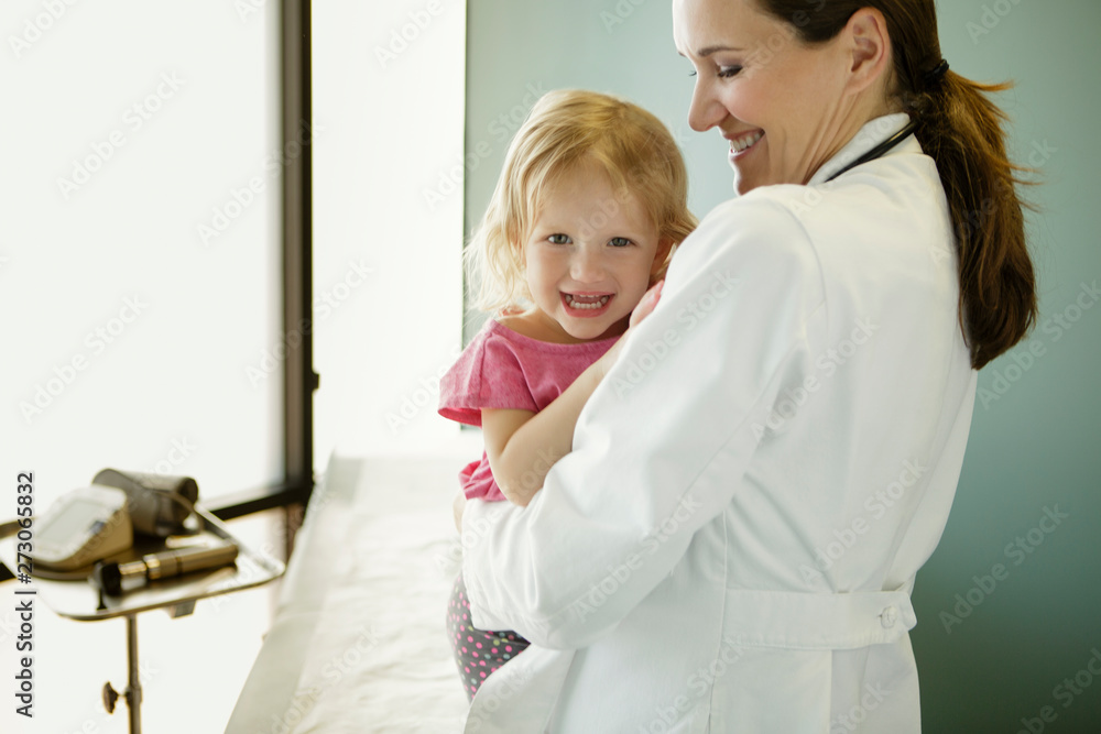 Woman doctor holding smiling young patient Woman doctor holding smiling young patient
