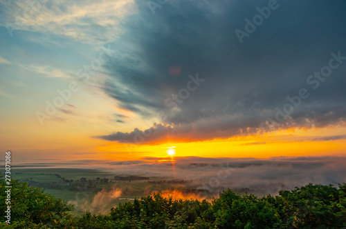 Sunrise on a foggy summer morning over the village