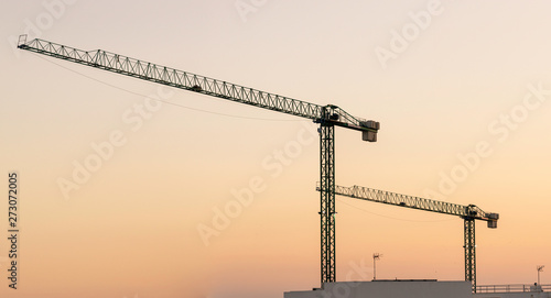 Silhouette of Tower construction crane and the building against a beautiful sky at sunset background