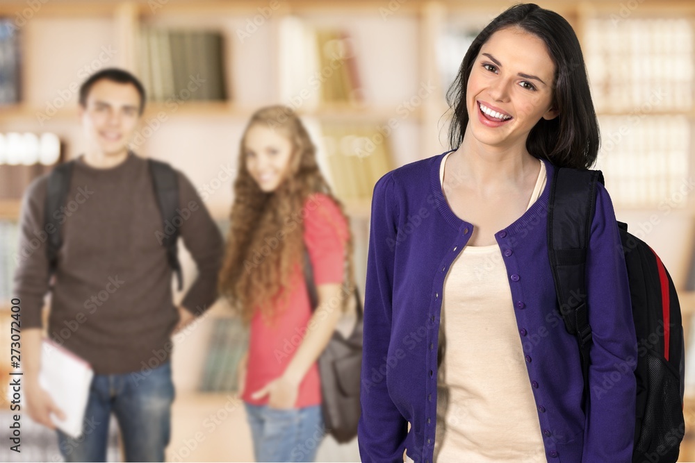 Young girl in Library Holding Notebooks in front of smiling students Young girl in Library Holding Notebooks in front of smiling students
