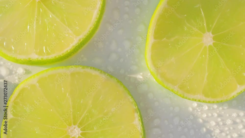 Sliding along lime slices on a white and wet background. Close up Sliding along lime slices on a white and wet background. Close up