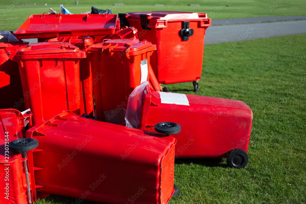 Red garbage containers on the green grass on the background of blue sky Red garbage containers on the green grass on the background of blue sky