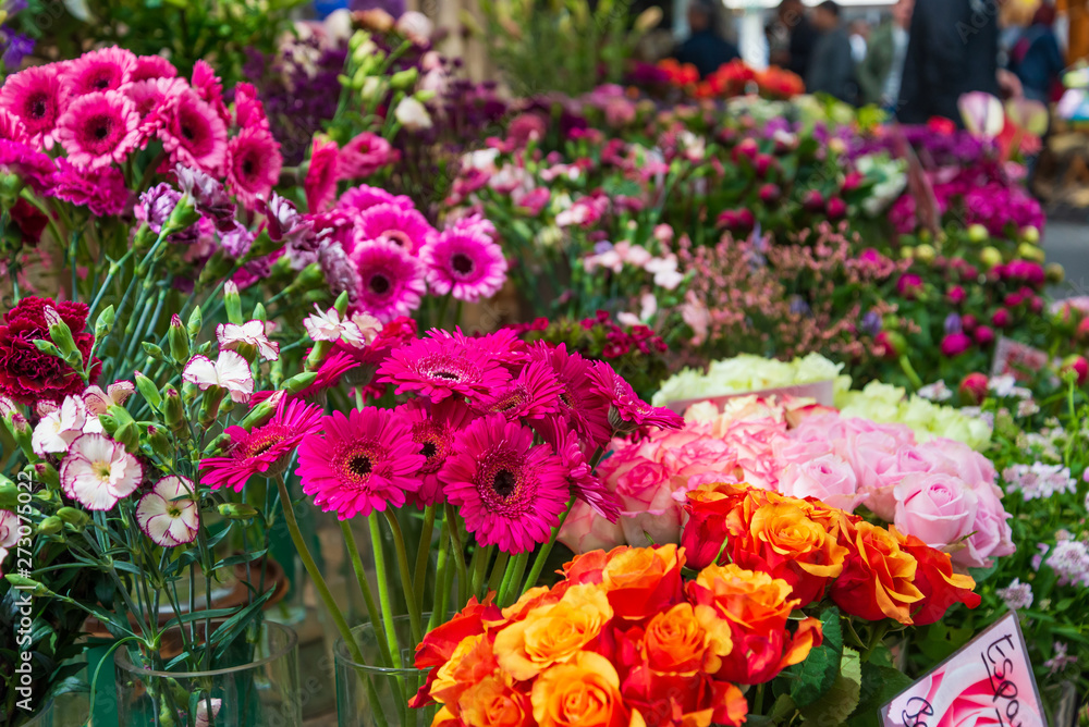 Closeup view of colourful various flowers in vases which are sold at open air flower stall or floral shop located in outdoor market in Europe. Typical atmosphere of flower store.   