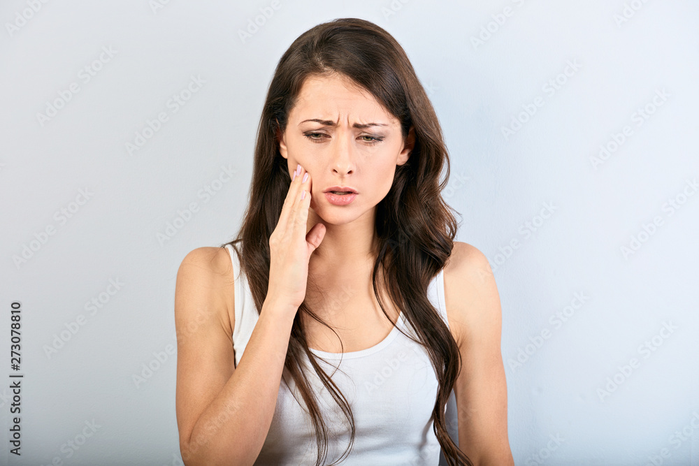 Tooth pain and dentistry. Beautiful young woman suffering from strong teeth pain and the hand touching the cheek. Female in casual clothing feeling painful toothache. Tooth pain and dentistry. Beautiful young woman suffering from strong teeth pain and the hand touching the cheek. Female in casual clothing feeling painful toothache.
