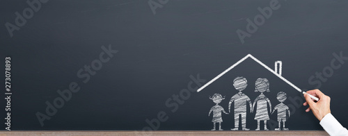 man is drawing roof on the family on chalkboard. home ownership concept