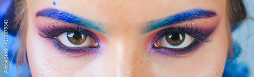 Beautiful macro shot of female eye with colorful makeup. Perfect shape of eyebrows, rainbow eyeshadows and long eyelashes. Cosmetics and make-up. Closeup macro shot of fashion liner eyes visage.