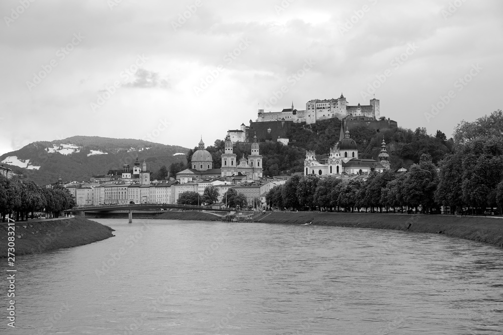 Obraz premium Landscape, with Hohensalzburg castle on Festung mountain in Salzburg, Austria. View from the Salzach river in overcast weather black and white photo