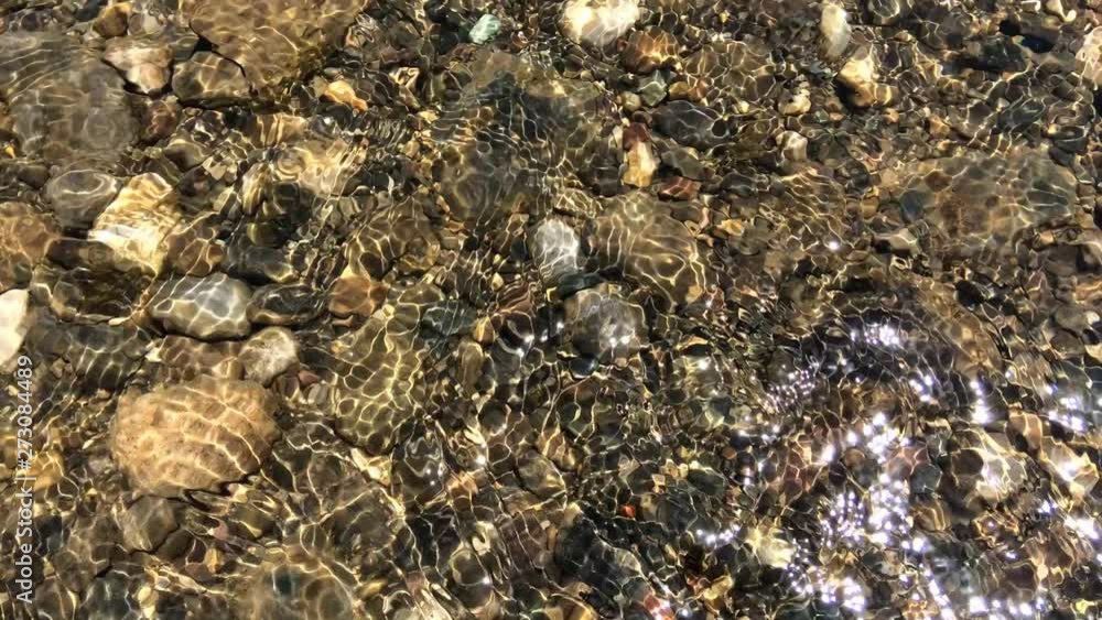 Stone under river water wave.Stones under river water flow. The rays of the sun on the stream of river water. Stone under river water wave.Stones under river water flow. The rays of the sun on the stream of river water.